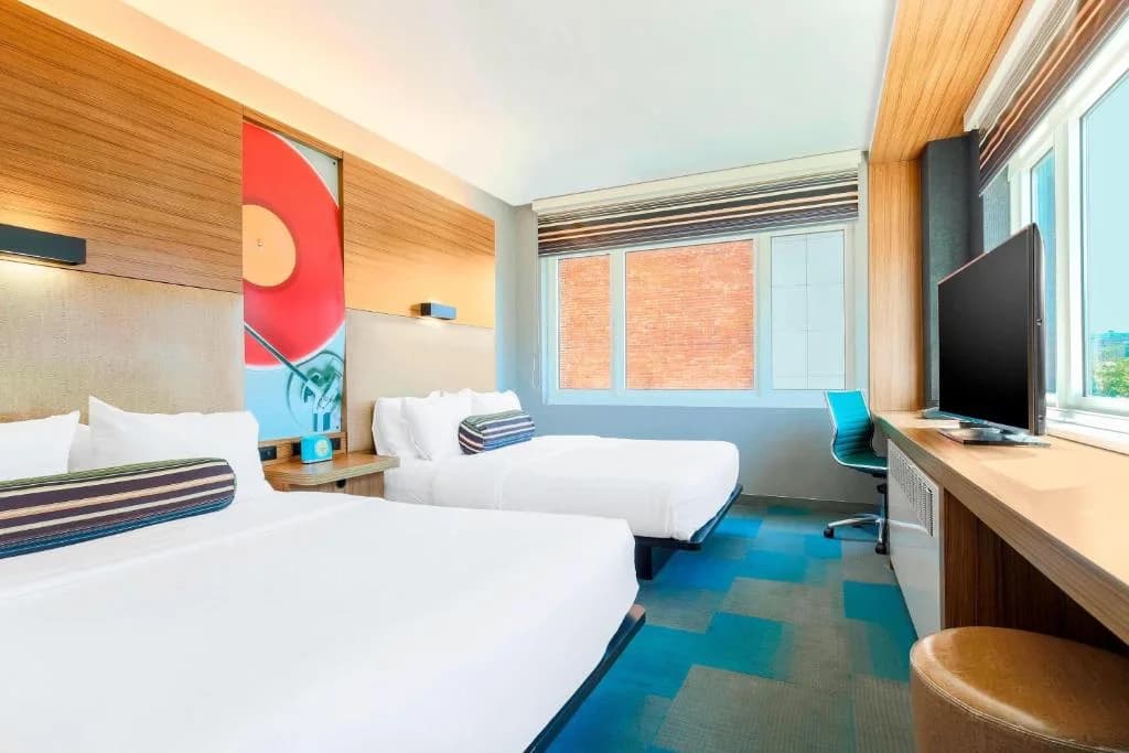 a hotel room with two beds and a flat screen tv at Aloft by Marriott Harlem in New York