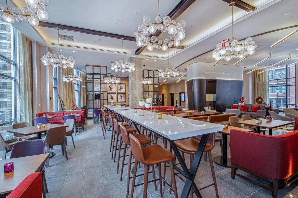 a restaurant with tables and chairs and chandeliers at Canopy By Hilton Jersey City Arts District in Jersey City