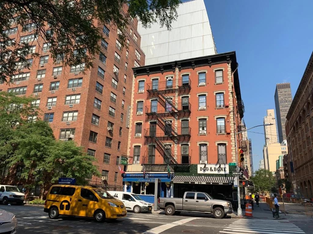 a busy city street with cars and a yellow taxi at Carlton Arms Hotel in New York