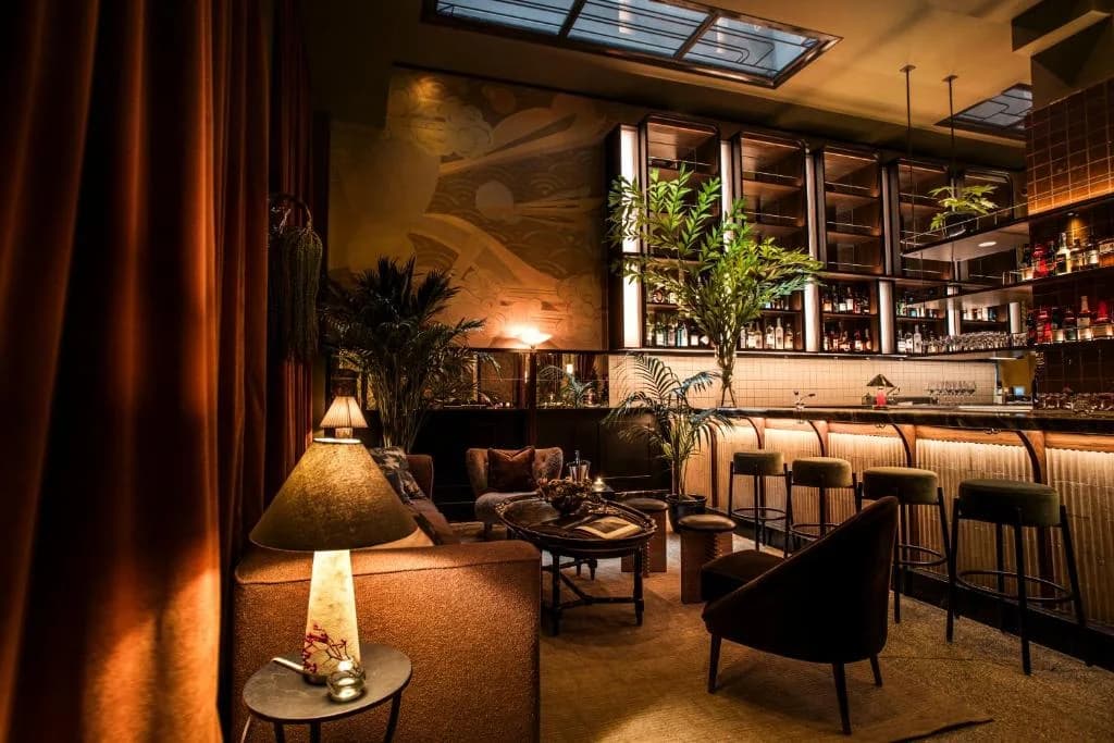 a room with a bar with chairs and a table at The Evelyn NoMad in New York