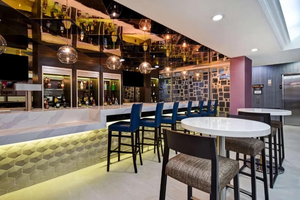 a restaurant with a bar with blue chairs and tables at Hampton Inn NY-JFK in Queens