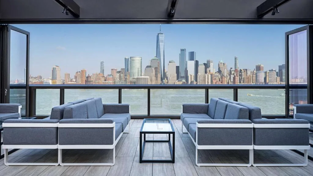 a living room with couches and a view of a city at Hyatt House Jersey City in Jersey City