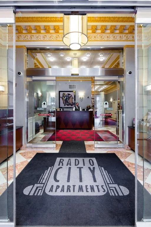 a lobby with a large glass door with a raisin city organizations sign at Radio City Apartments in New York
