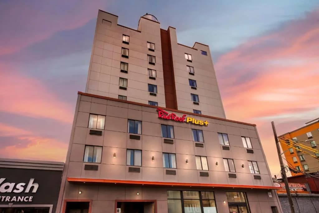 a building with a red hotel sign on top of it at Red Roof Inn PLUS Jamaica, NY - JFK Airport in Jamaica