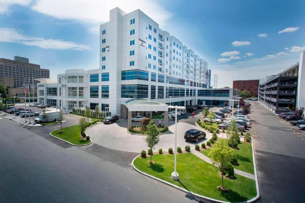 a large white building with cars parked in a parking lot at Residence Inn by Marriott The Bronx at Metro Center Atrium in Bronx
