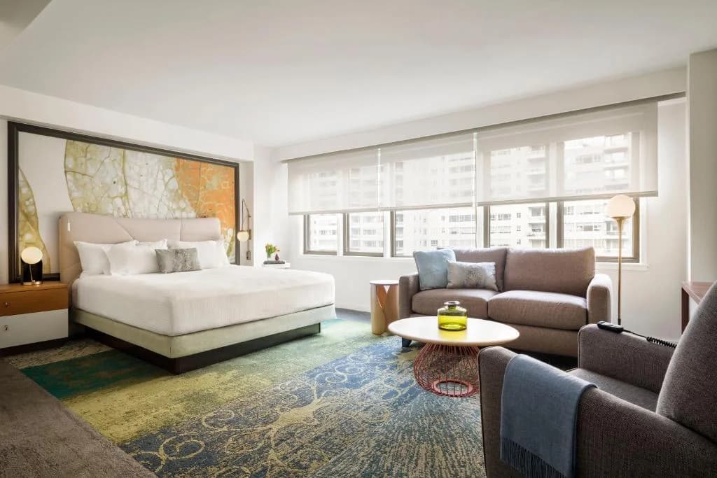 a bedroom with a bed and a couch and a table at The Gardens Sonesta ES Suites New York in New York