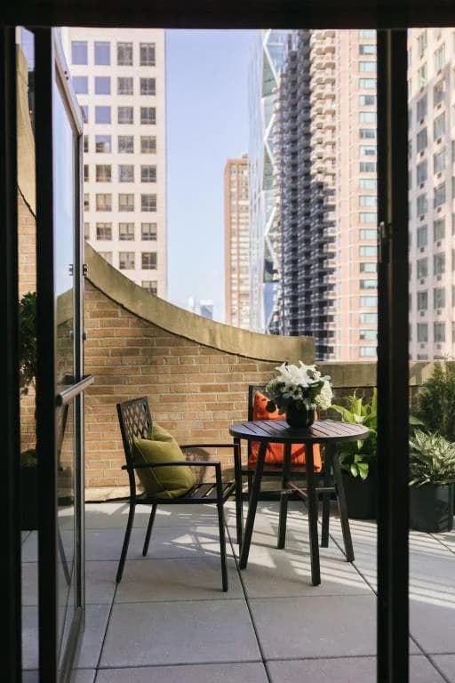 a table and chairs on a balcony with a view of a city at The Manhattan Club in New York