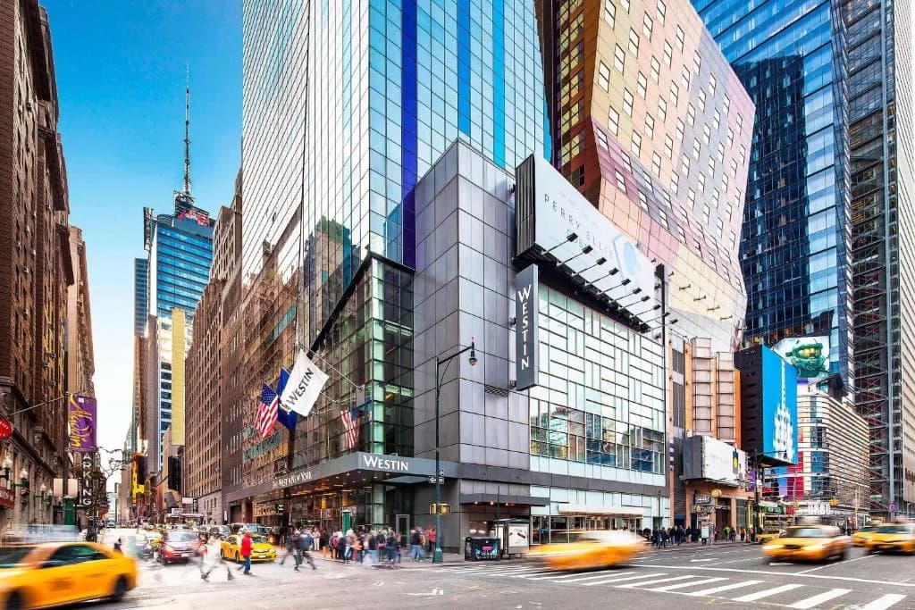 a busy city street with traffic and taxis in front of a building at The Westin New York at Times Square in New York