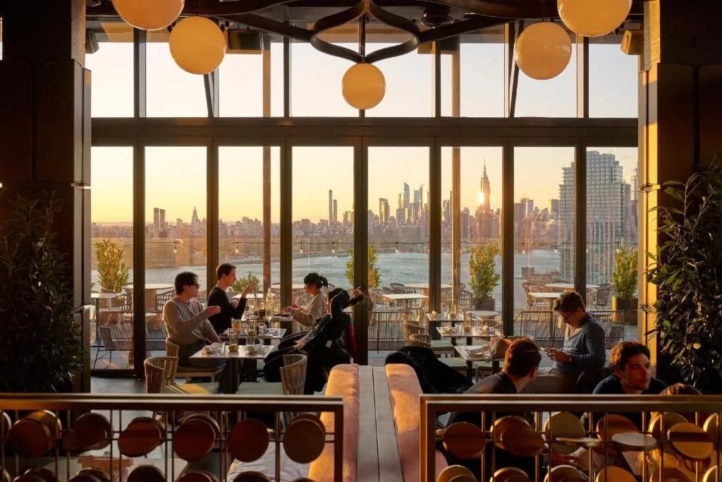 a group of people sitting at tables in a restaurant at The William Vale in Brooklyn