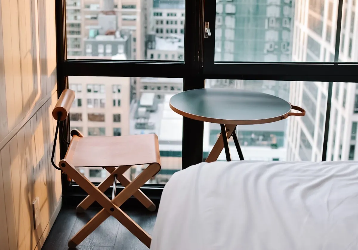 A stylish hotel room in New York City with a cityscape view, blending modern and minimalist design.