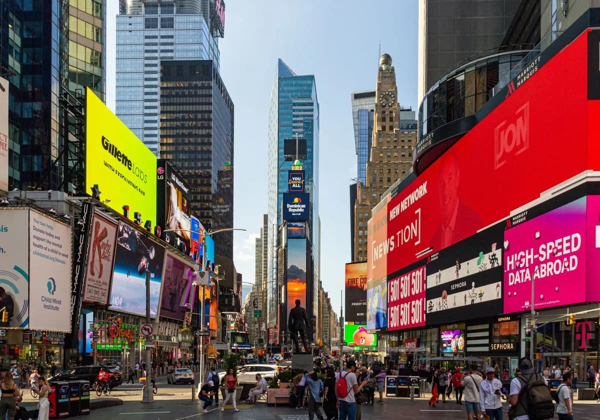 Bustling Times Square NYC with vibrant billboards and lively crowd under a bright sky.