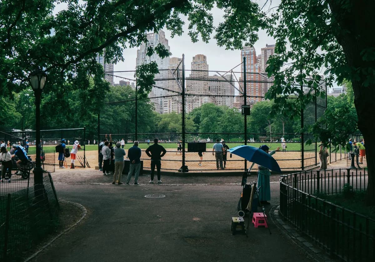 A baseball game in Central Park with Manhattan skyscrapers in the background.