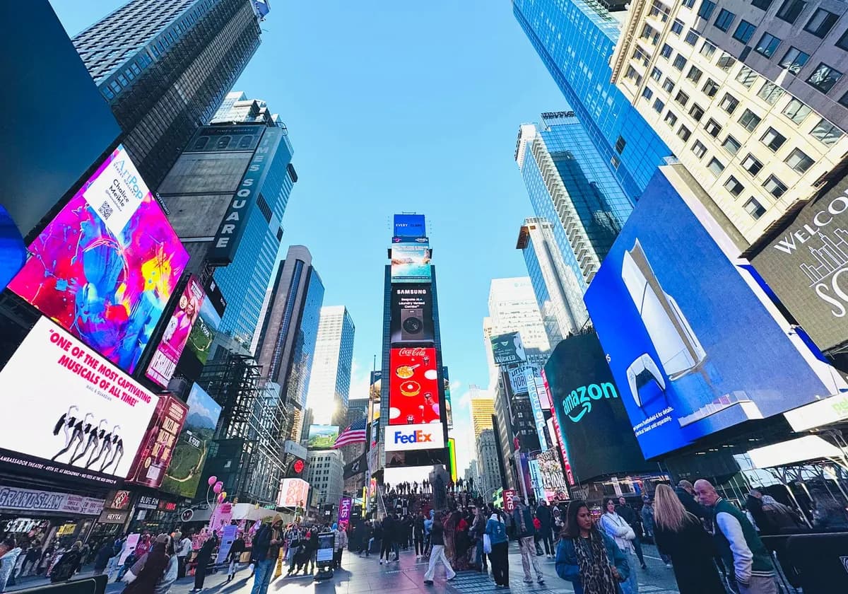 Vibrant daytime view of Times Square, showcasing iconic billboards and bustling crowd in New York City.