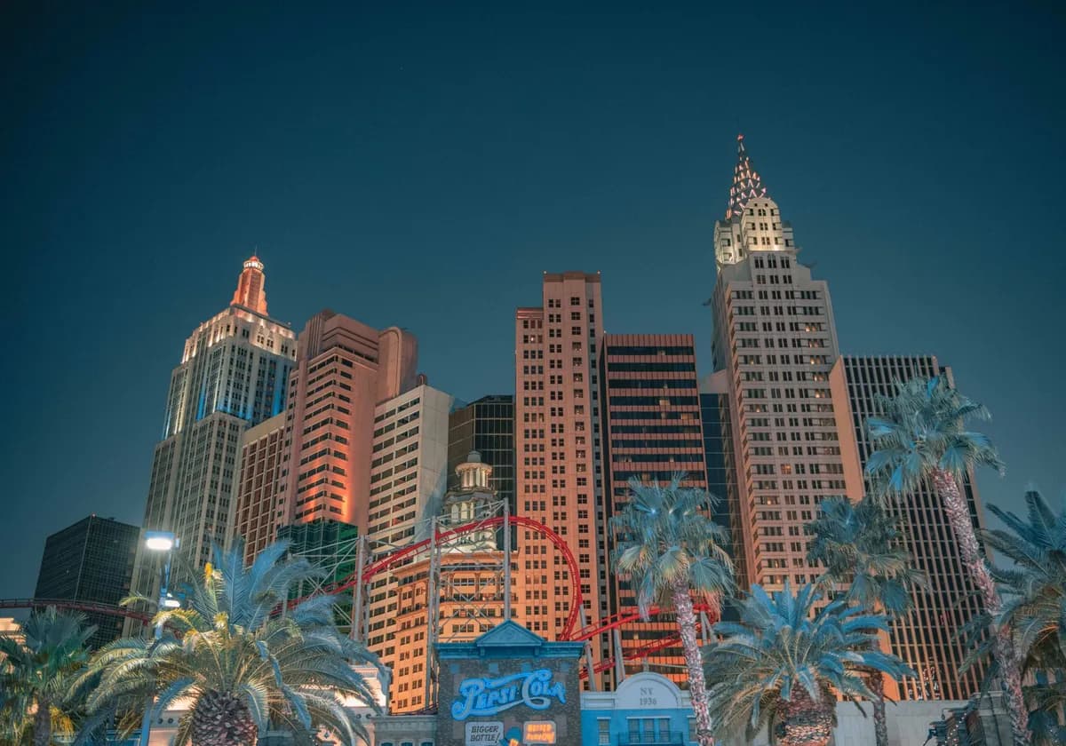 Night view of the Las Vegas skyline featuring iconic skyscrapers and an illuminated roller coaster.