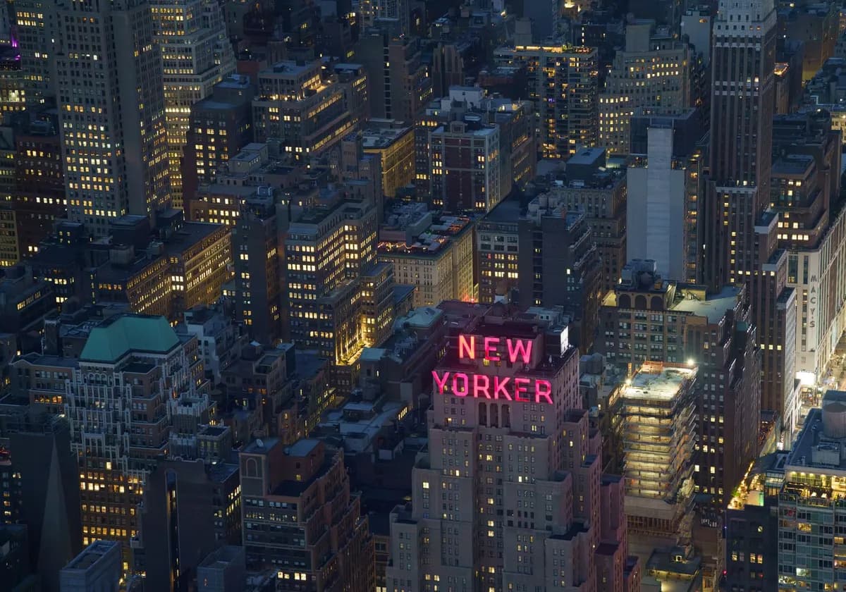 A captivating aerial shot of New York City featuring the illuminated New Yorker Hotel.