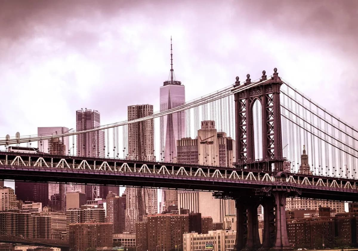 Dramatic view of Manhattan Bridge with New York City skyline in a sepia tone.