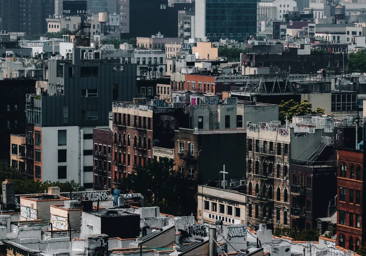 Aerial view of diverse urban rooftops in New York City, showcasing graffiti and architectural variety.