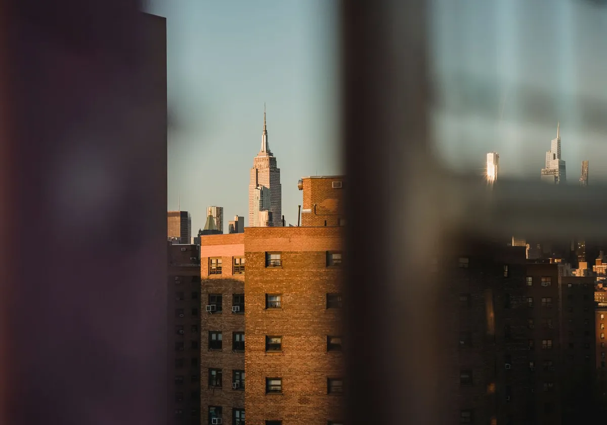 Through fence view of aged multistory house exteriors under light sky in town in evening