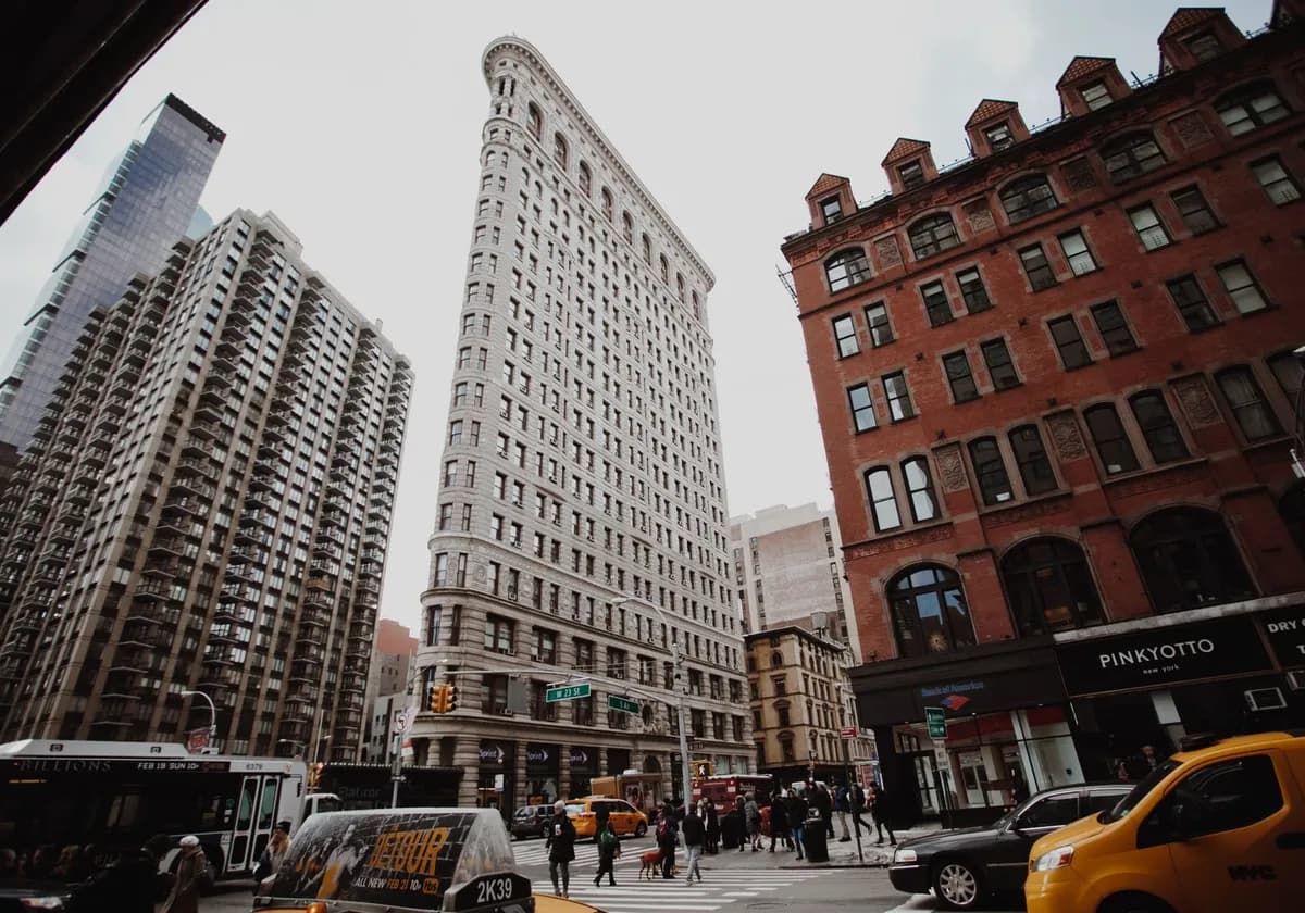 Dramatic cityscape view of New York's iconic Flatiron Building amidst bustling street traffic.