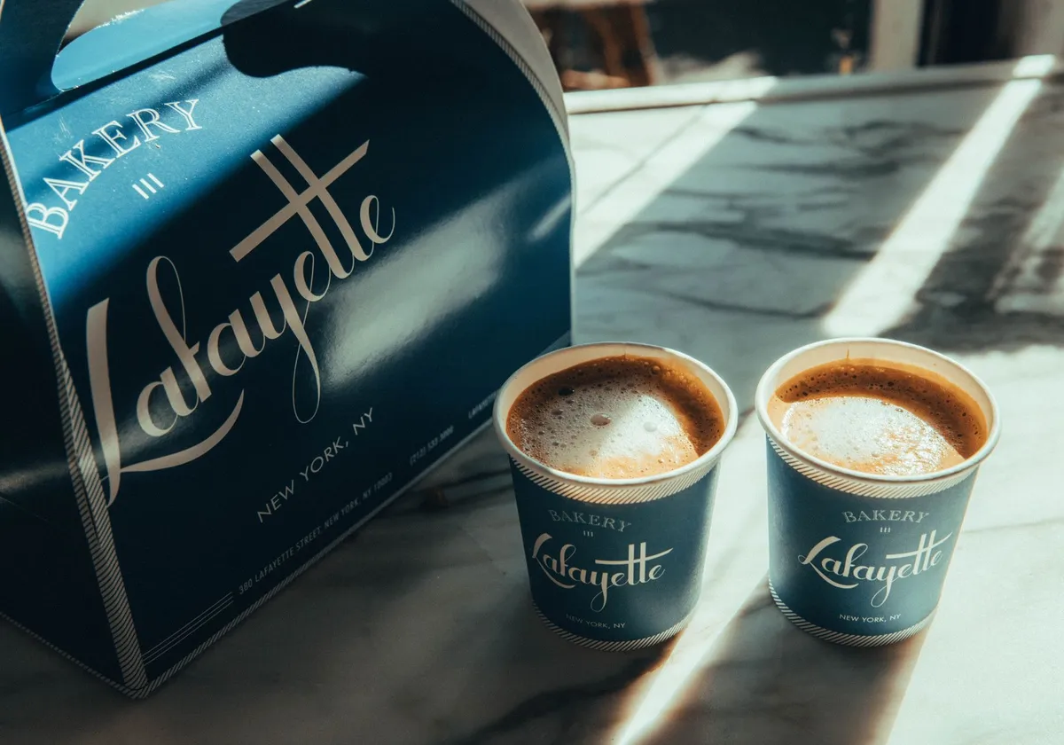 Sunlit coffee cups and bakery box at Lafayette in New York City