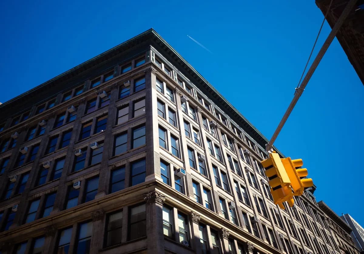 A classic New York City building with a traffic light under a clear blue sky.