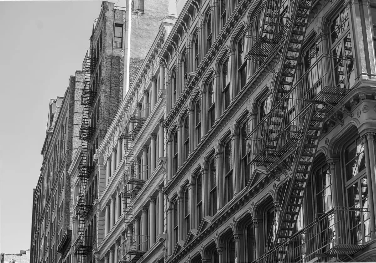 Monochrome view of historic city buildings featuring fire escapes, showcasing urban architecture.