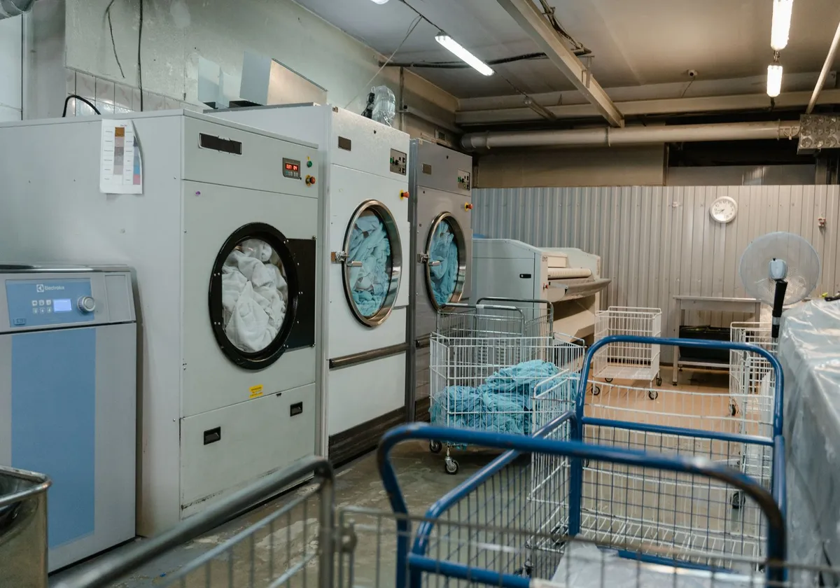 Interior view of an industrial laundry room with washers and rolling carts.