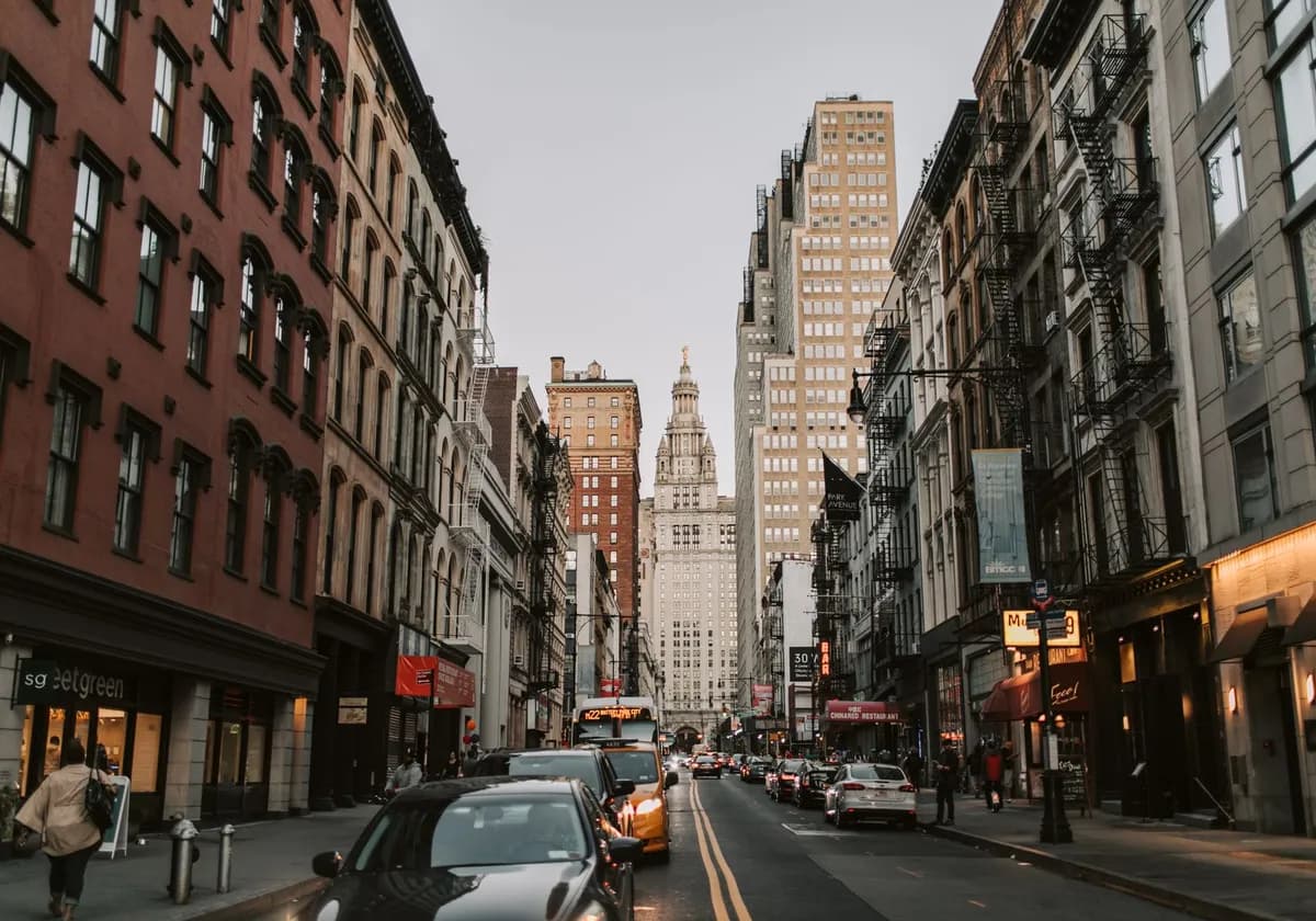 Dynamic street scene with historic facades leading to iconic skyscrapers in New York City.