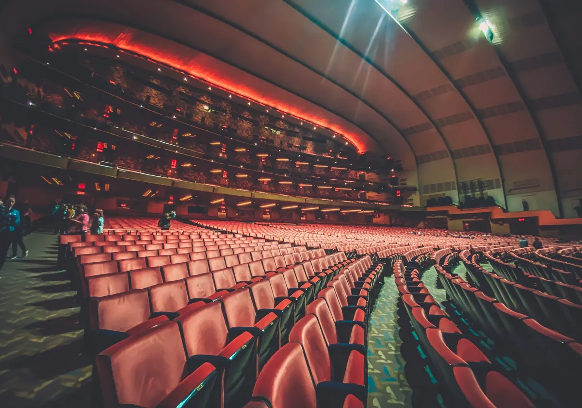 Expansive interior of a modern theater with rows of empty seats and warm lighting creating an inviting atmosphere.