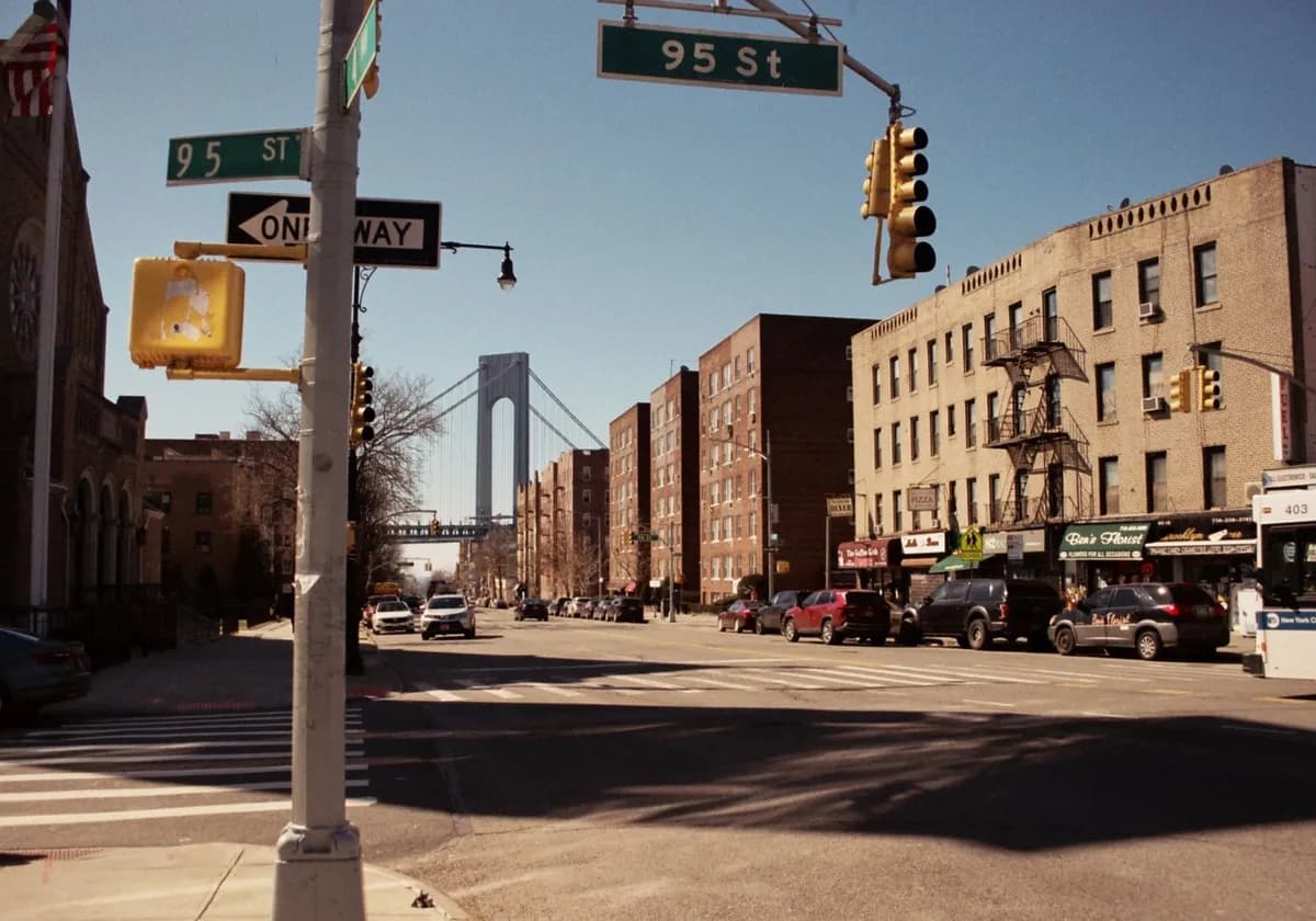City street view with buildings, traffic lights, and a bridge under a clear sky.