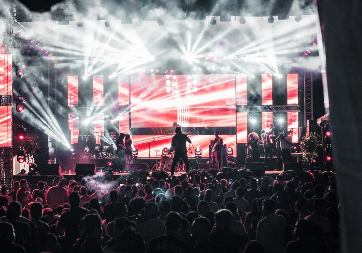 Energetic live music concert featuring performers on a vibrant stage, captivating a large audience.