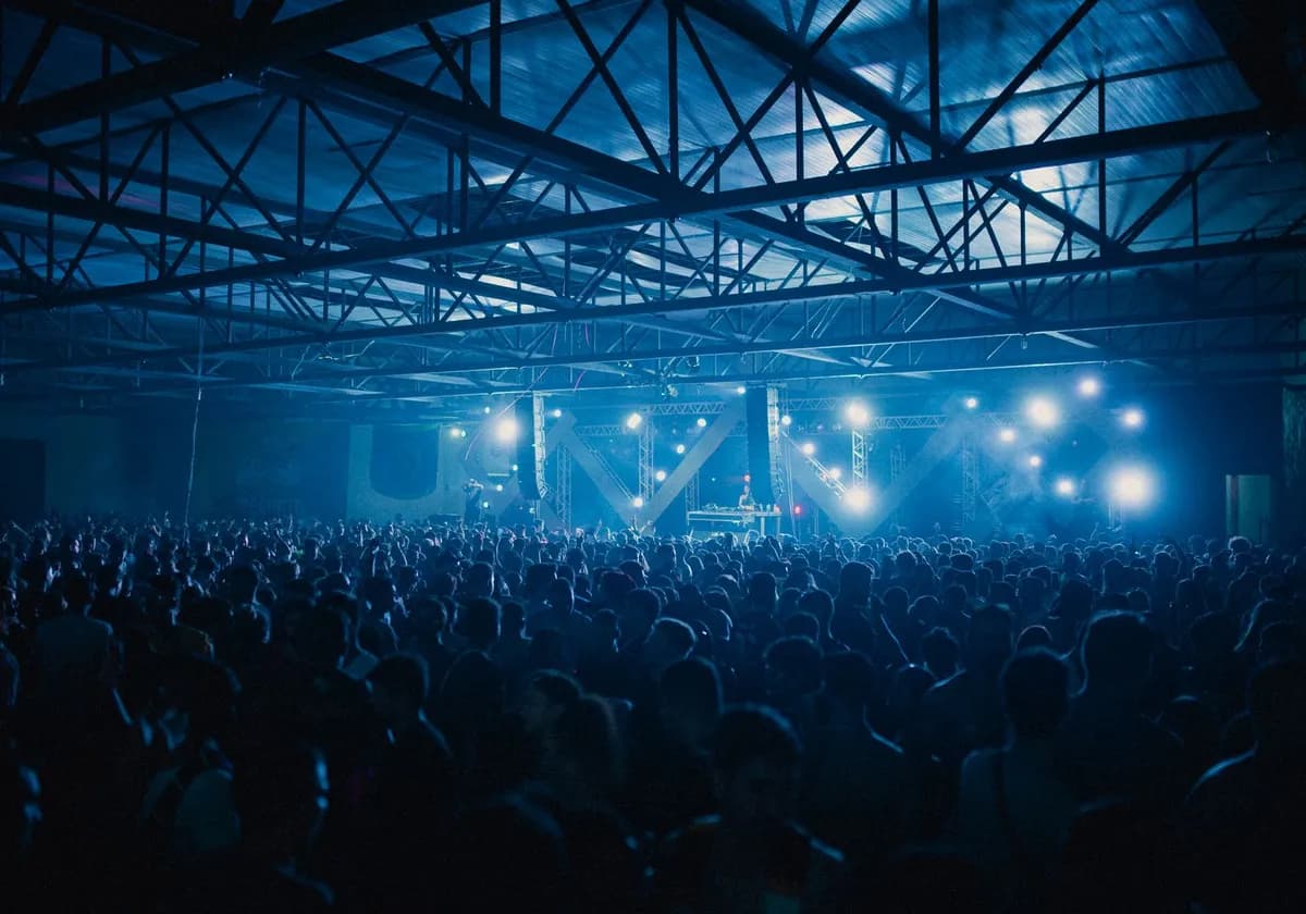 A vibrant indoor concert with a large energetic crowd enjoying the live performance.