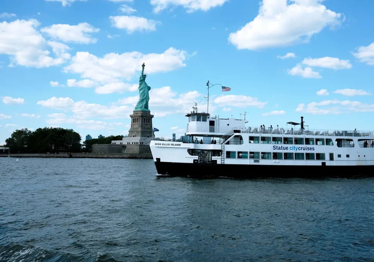 Scenic view of the Statue of Liberty and ferry boat in Jersey City under a bright summer sky.