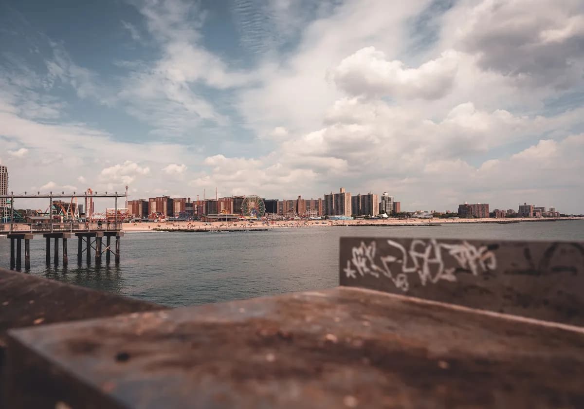 View of Coney Island's coastline with urban backdrop and iconic amusement park.