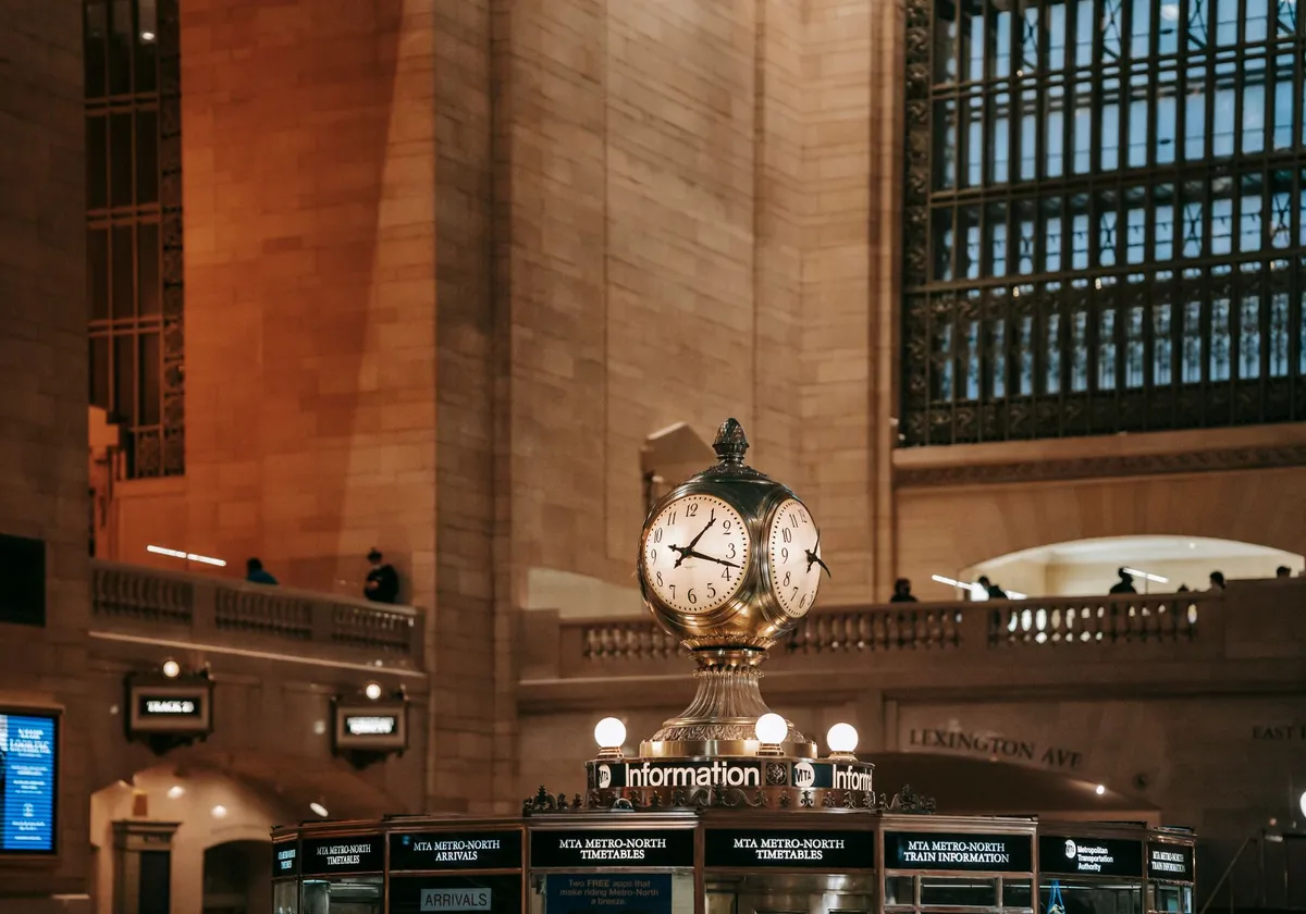 Interior of Grand Central Terminal building with glass windows under lattice in brick walls and classic watch in center of hall