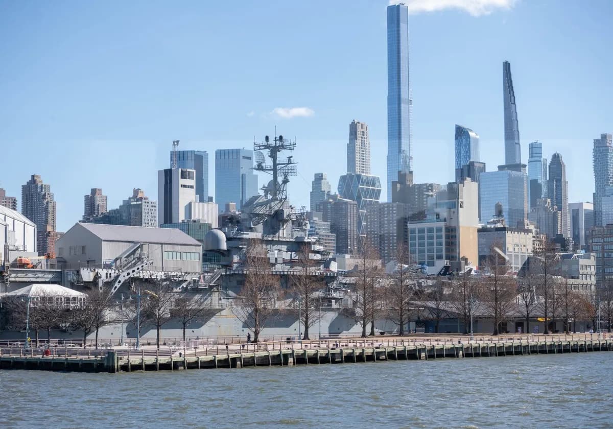 USS Intrepid museum ship with NYC skyscrapers in the background.