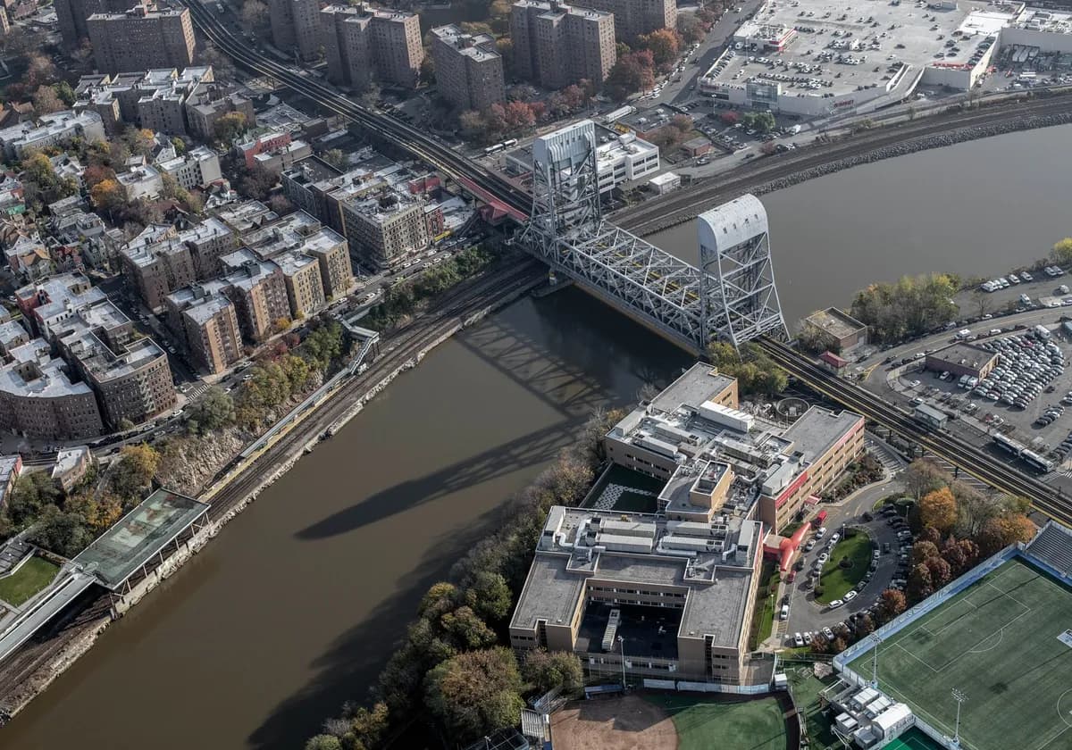 Aerial shot of New York City's urban landscape featuring a bridge over a river and residential buildings.
