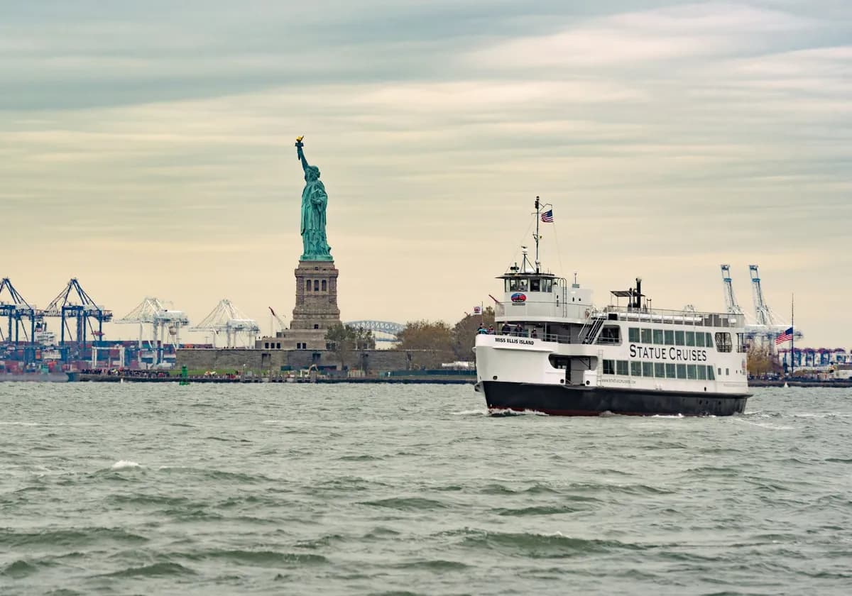 A ferry cruises past the iconic Statue of Liberty in New York Harbor, USA.