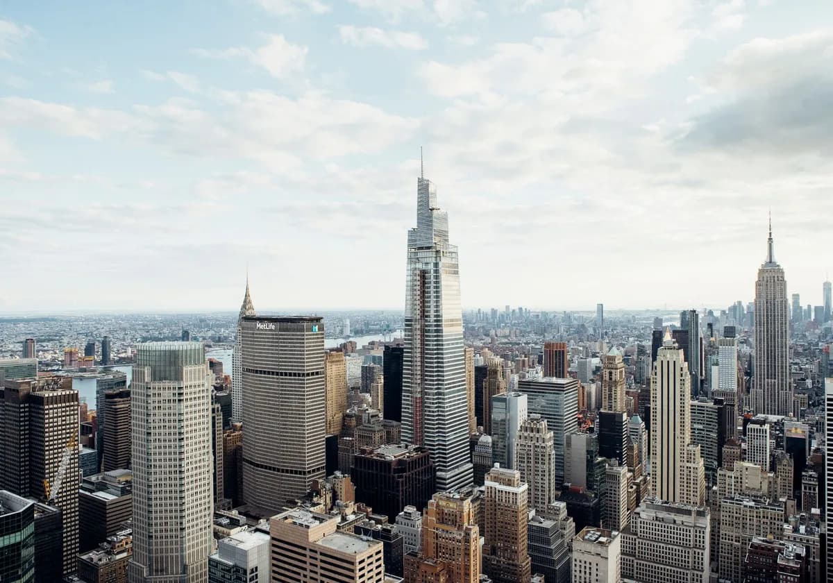 Drone view of modern high rise houses and empire state building located against cloudy sky in downtown of New York city