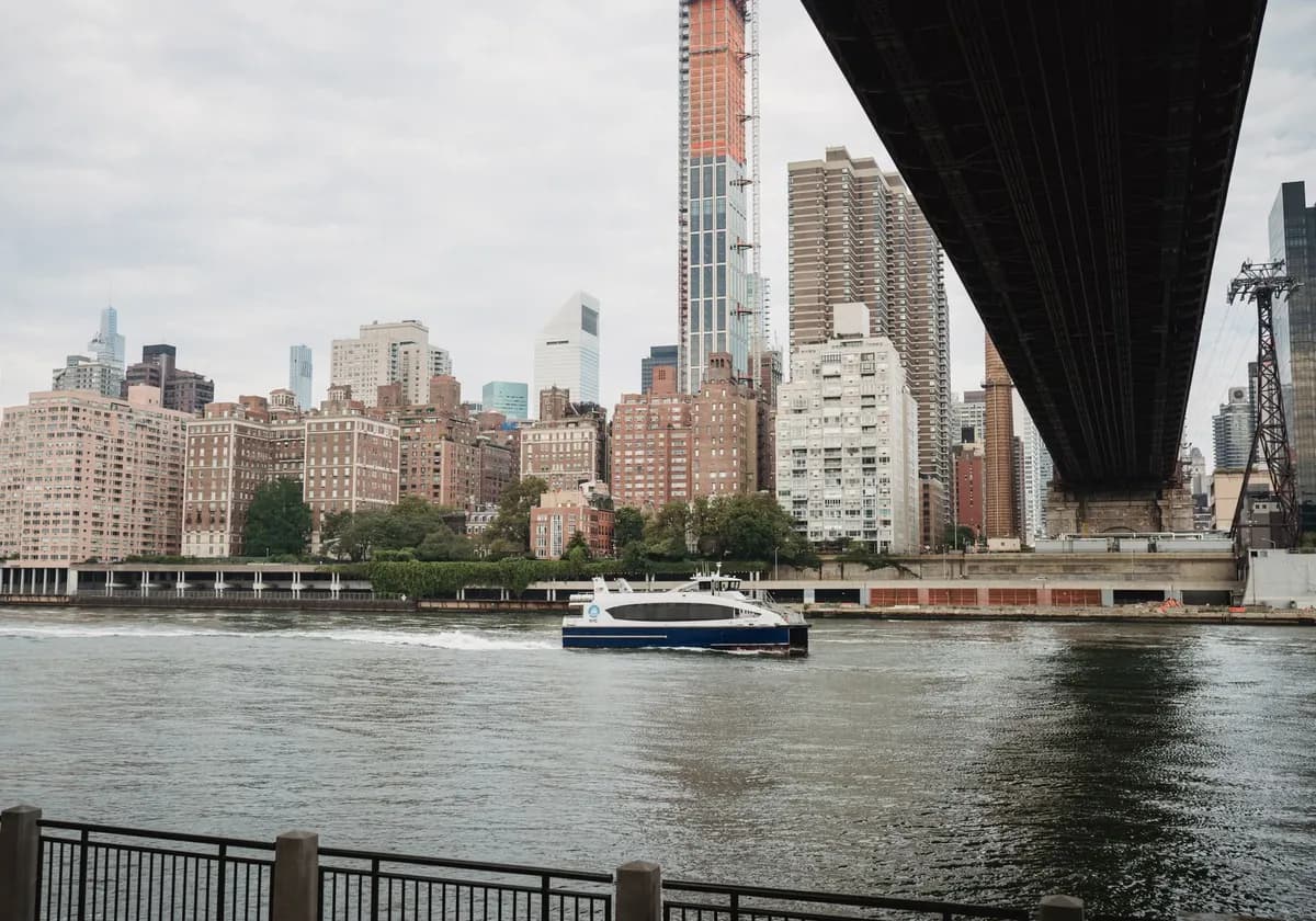 Modern boat floating on calm river channel near bridge in modern city in cloudy day