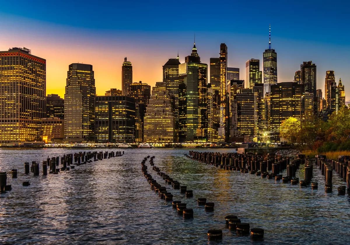 Captivating view of New York City's illuminated skyline at sunset over the waterfront.