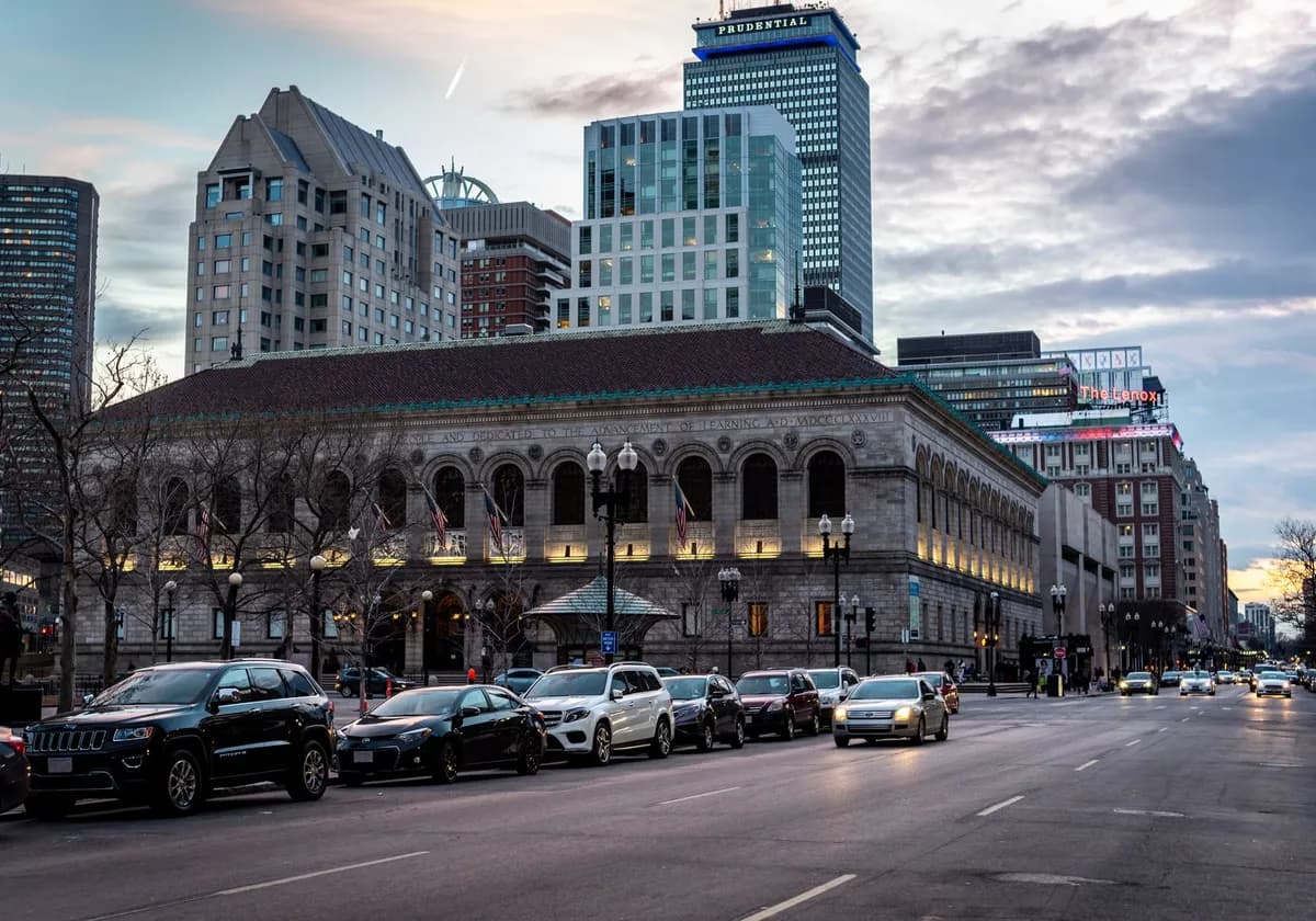 A street view of Boston Public Library and skyline at dusk, capturing urban architecture and city life.