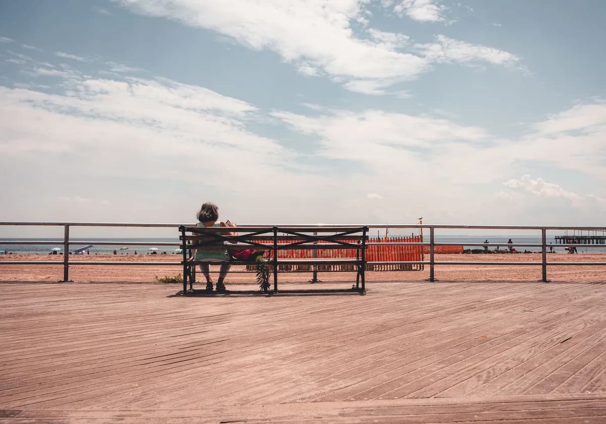 A serene scene featuring a wooden bench on a beachfront boardwalk with ocean views.