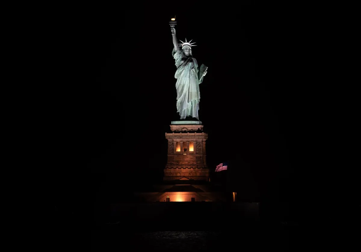Iconic Statue of Liberty illuminated against a dark night sky in New York City, USA.