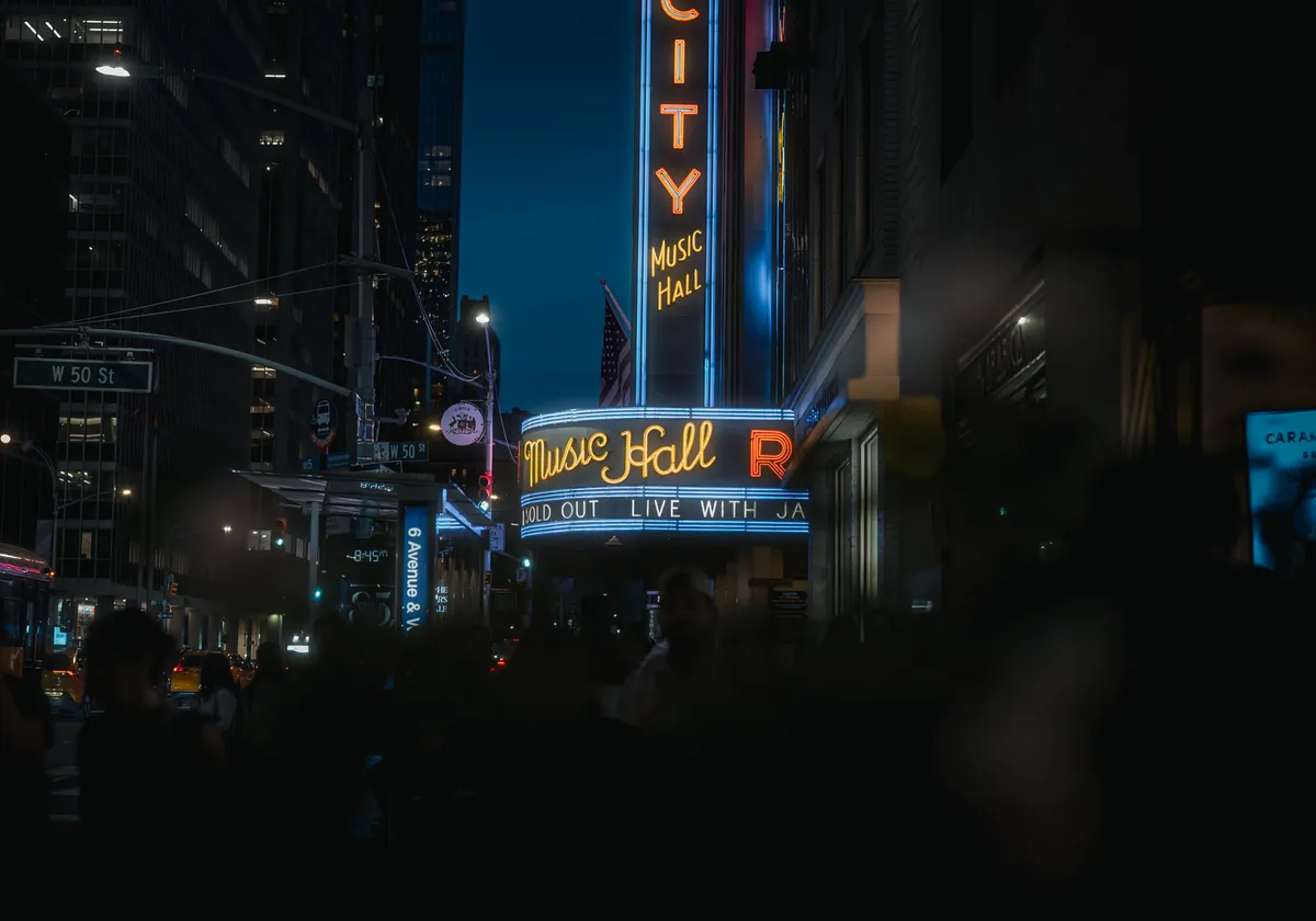 Neon lights illuminate the iconic Radio City Music Hall in New York City at night.