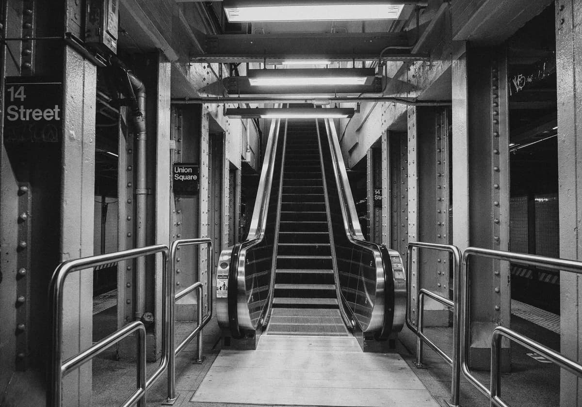 A grayscale image of a subway station escalator at Union Square, New York City.
