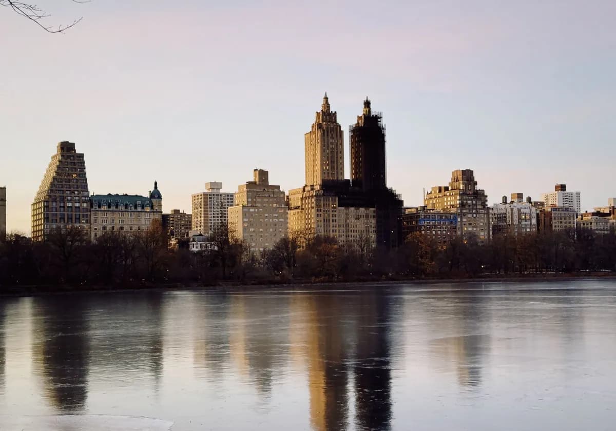Beautiful dusk view of New York City's skyline with reflections on a calm water surface.