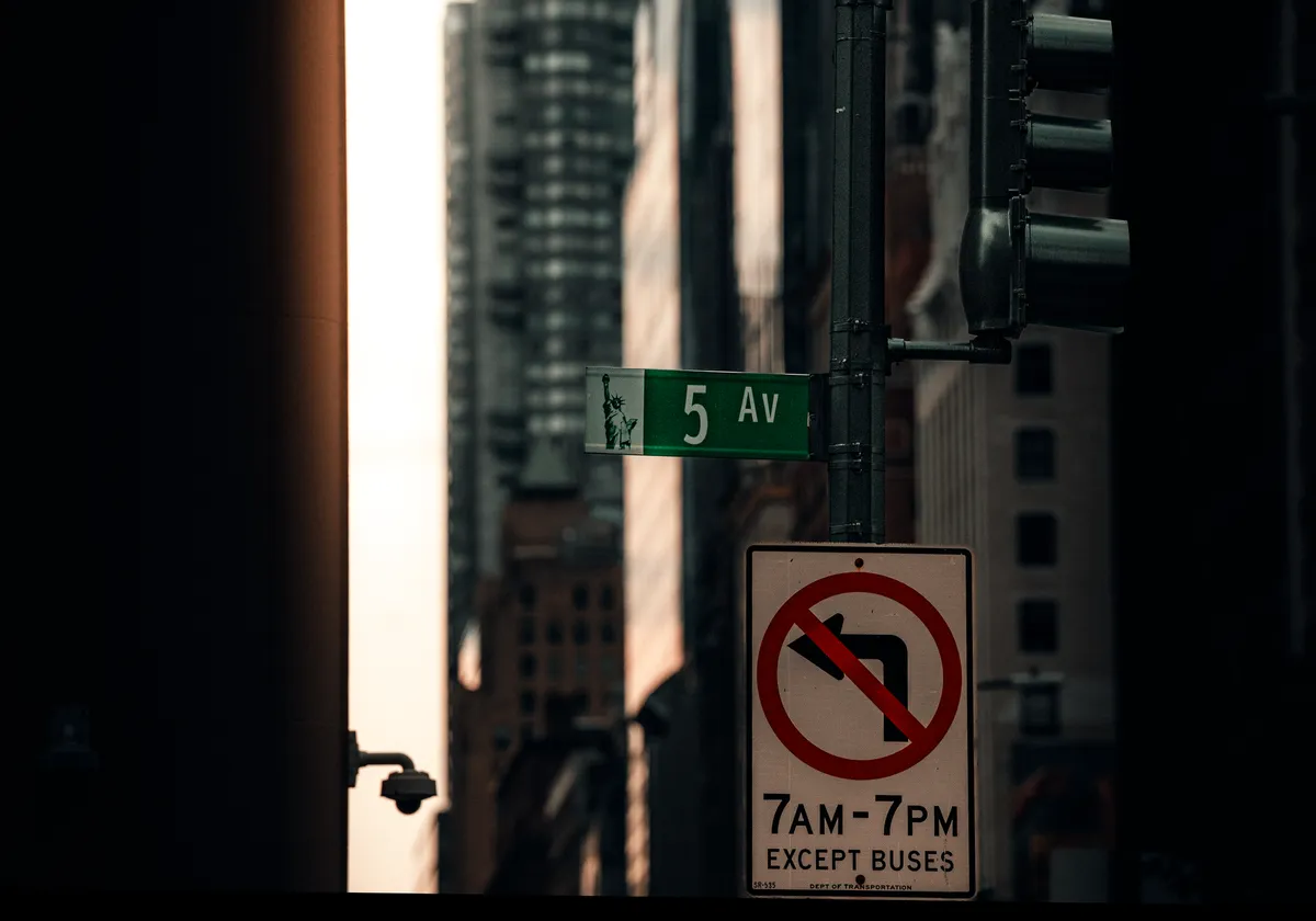 Moody urban scene of 5th Avenue street sign with tall buildings in NYC.