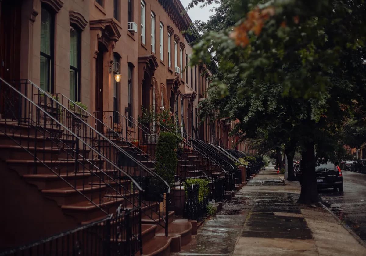 A rainy day in a historic New York neighborhood with classic brownstone buildings.
