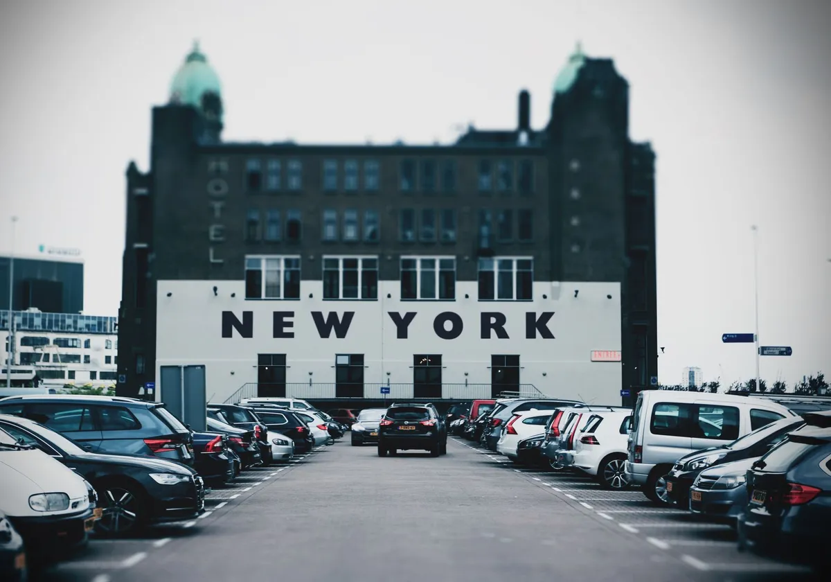 View of a parking lot with cars and a building featuring bold New York text.